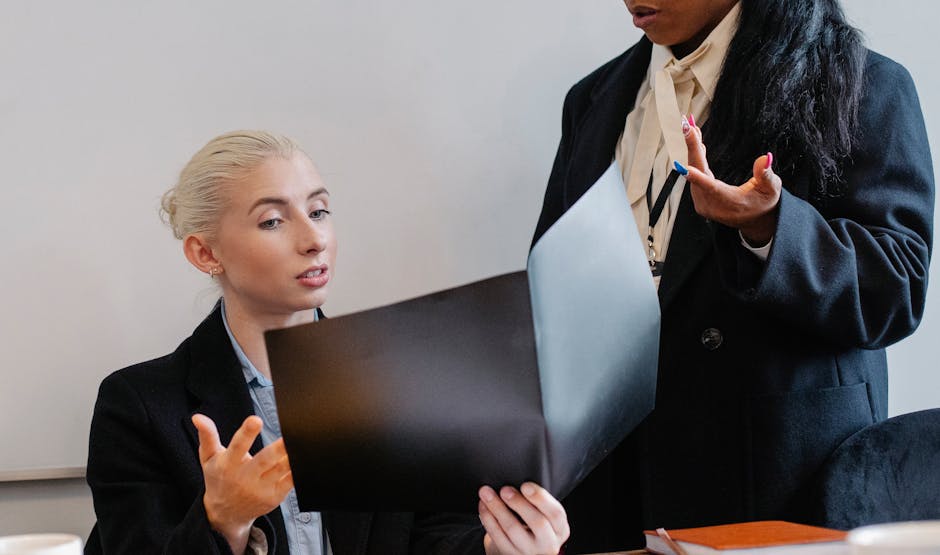 Concentrated multiracial coworkers looking through documents and discussing business issues while working in office